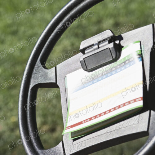 Steering wheel for golf buggy with score card clipped on. Steering wheel for golf buggy with score card clipped on.