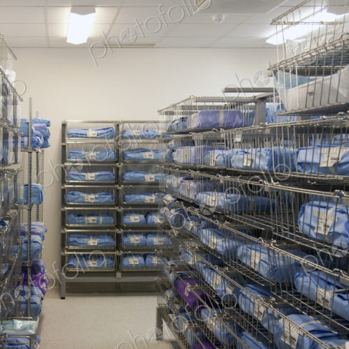 Storage room in a modern hospital, rows of sterile equipment packs in blue fabric.
