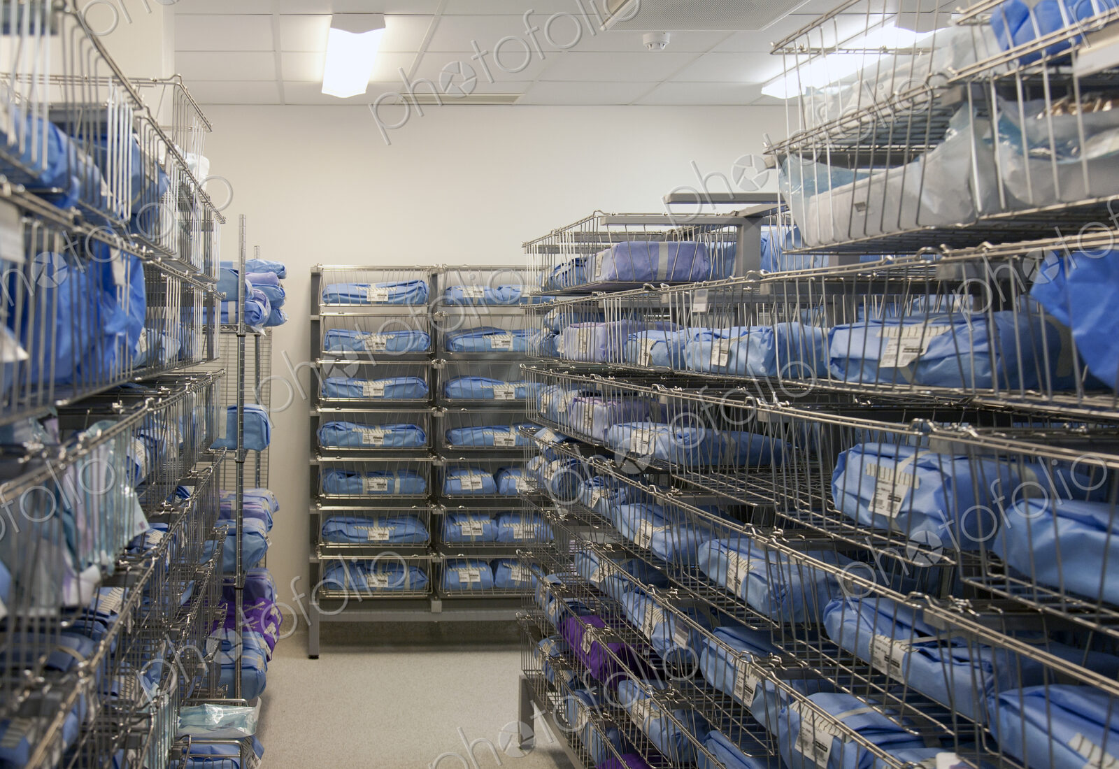Storage room in a modern hospital, rows of sterile equipment packs in blue fabric.