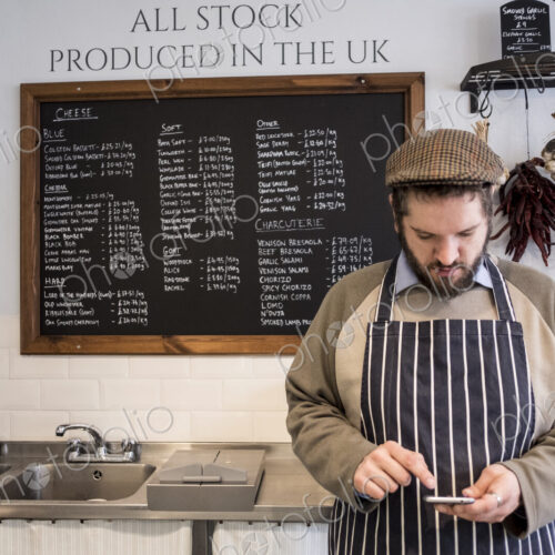 Store owner in a delicatessen using a digital tablet. Store owner in a delicatessen using a digital tablet.