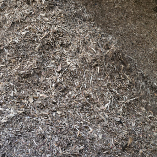 Stored organic waste heaped up in a large warehouse for biomass fuel production.