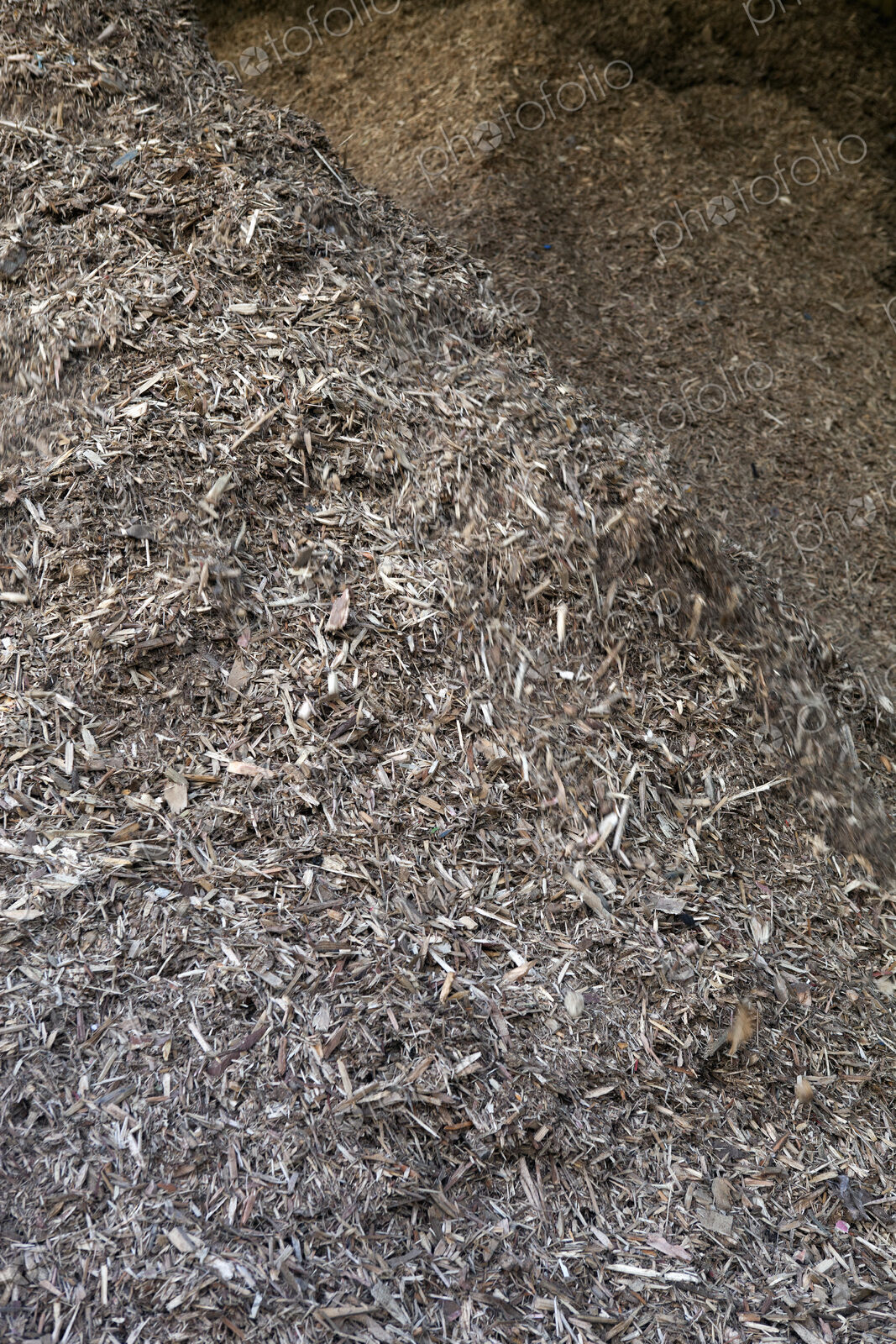 Stored organic waste heaped up in a large warehouse for biomass fuel production.