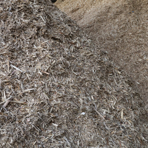 Stored organic waste heaped up in a large warehouse for biomass fuel production.