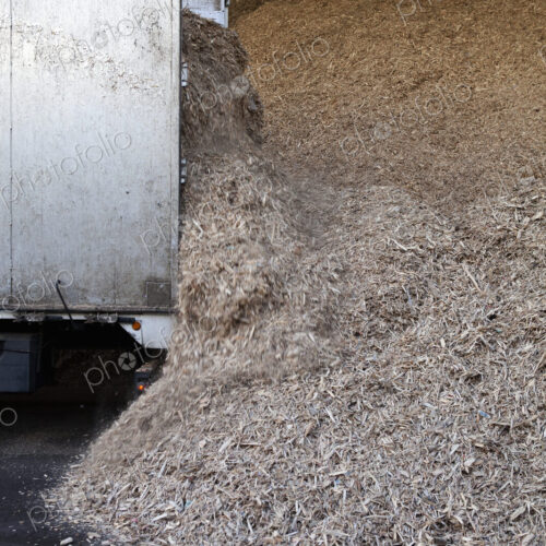 Stored organic waste heaped up in a large warehouse for biomass fuel production.