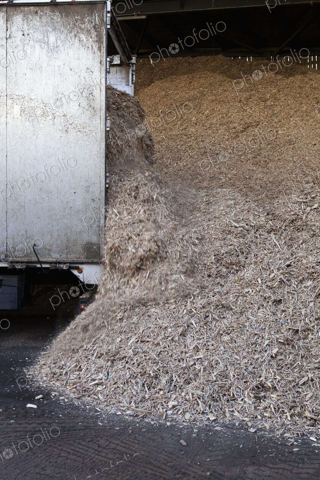 Stored organic waste heaped up in a large warehouse for biomass fuel production.