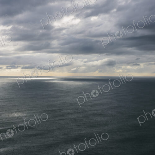 Storm clouds clearing over expansive ocean, dappled sunlight on water, northern Oregon…
