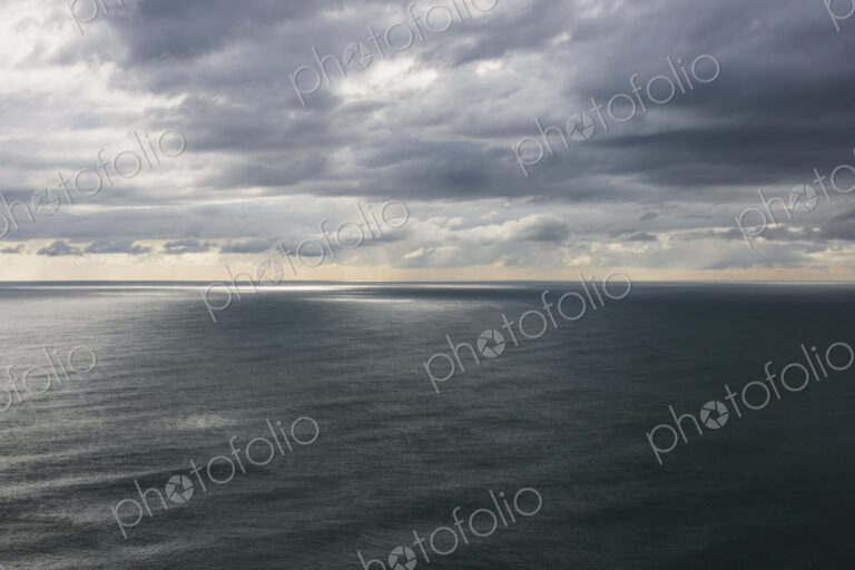 Storm clouds clearing over expansive ocean, dappled sunlight on water, northern Oregon…