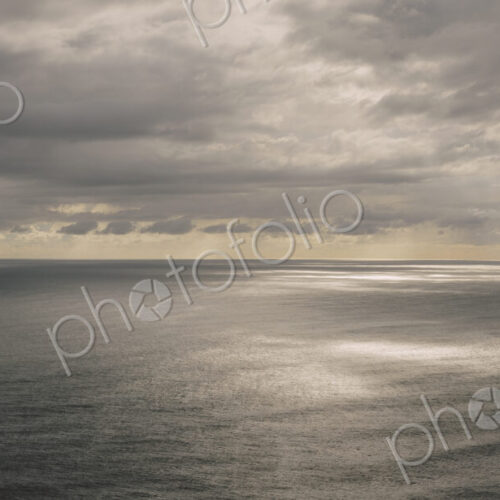 Storm clouds clearing over expansive ocean, dappled sunlight on water, northern Oregon…