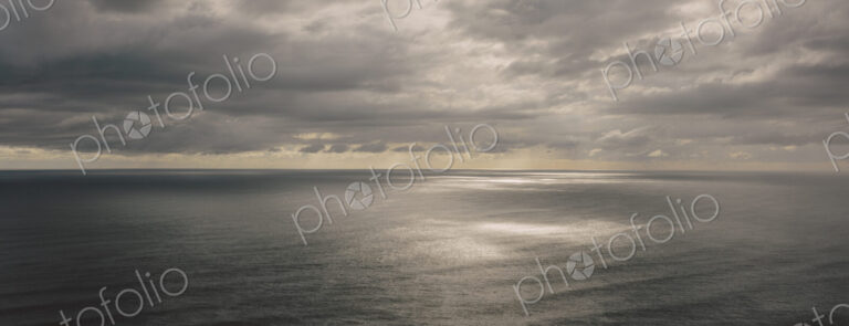 Storm clouds clearing over expansive ocean, dappled sunlight on water, northern Oregon…