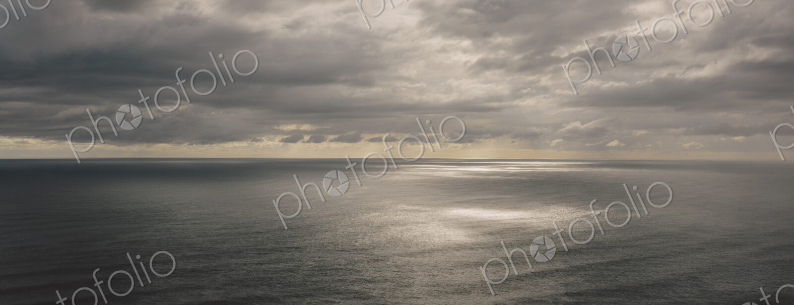 Storm clouds clearing over expansive ocean, dappled sunlight on water, northern Oregon…