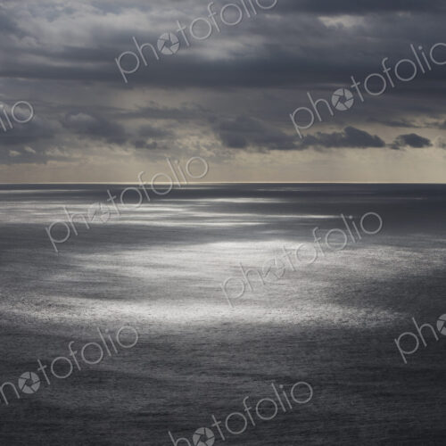 Storm clouds clearing over expansive ocean, dappled sunlight on water, northern Oregon…