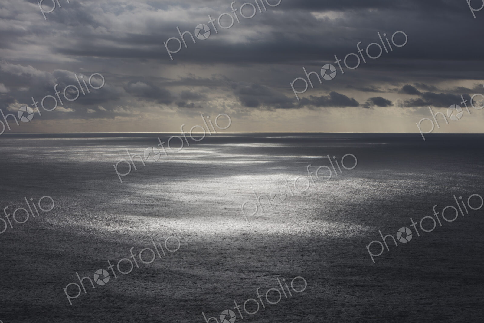 Storm clouds clearing over expansive ocean, dappled sunlight on water, northern Oregon…