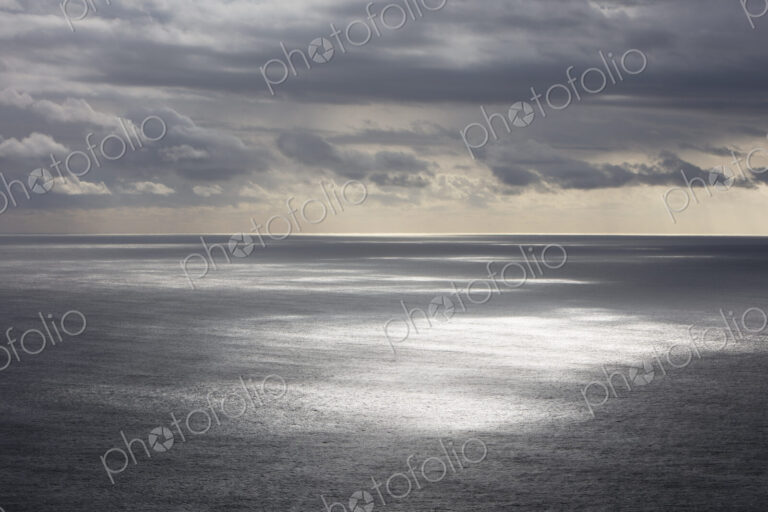 Storm clouds clearing over expansive ocean, dappled sunlight on water, northern Oregon…