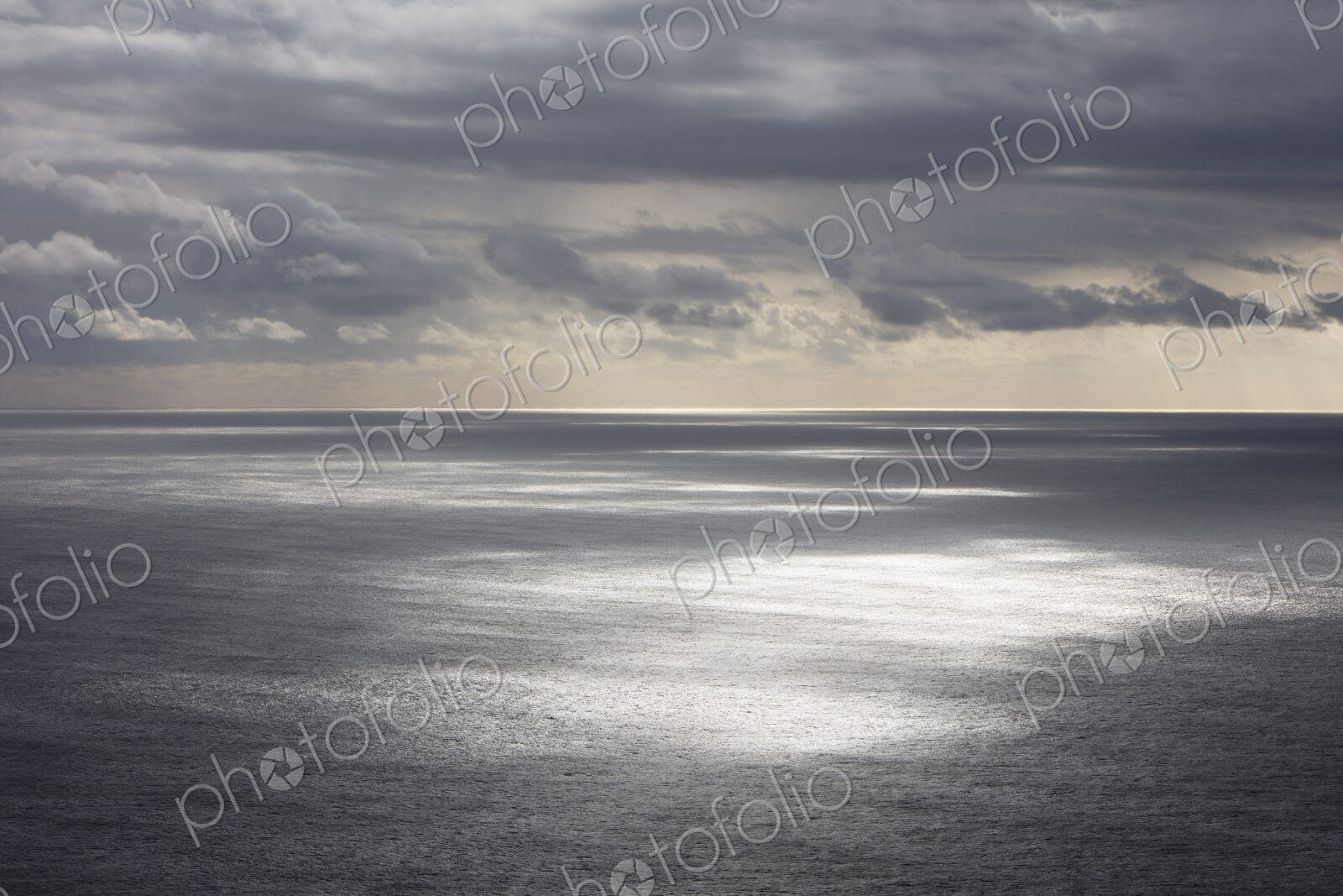 Storm clouds clearing over expansive ocean, dappled sunlight on water, northern Oregon…
