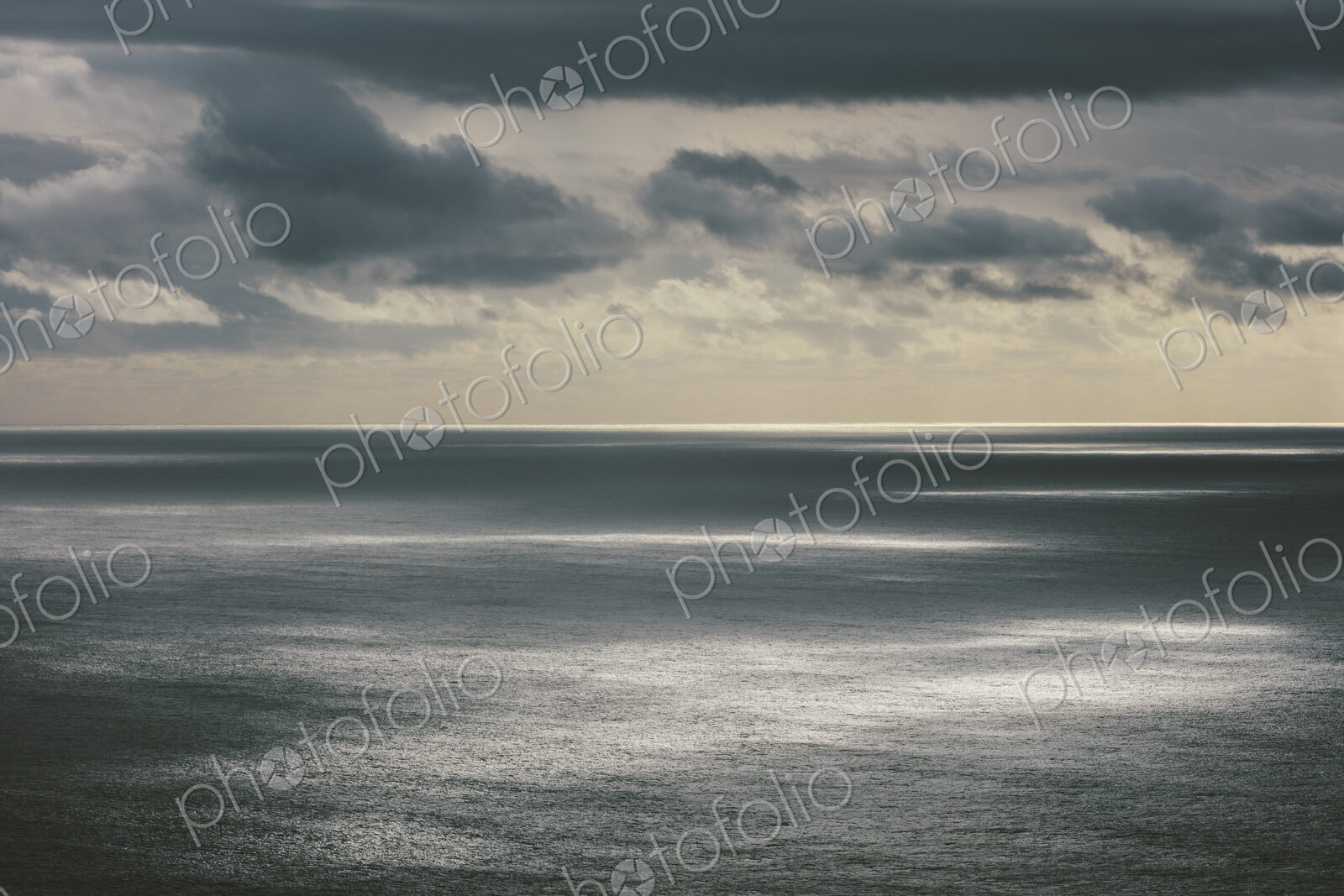 Storm clouds clearing over expansive ocean, dappled sunlight on water, northern Oregon…