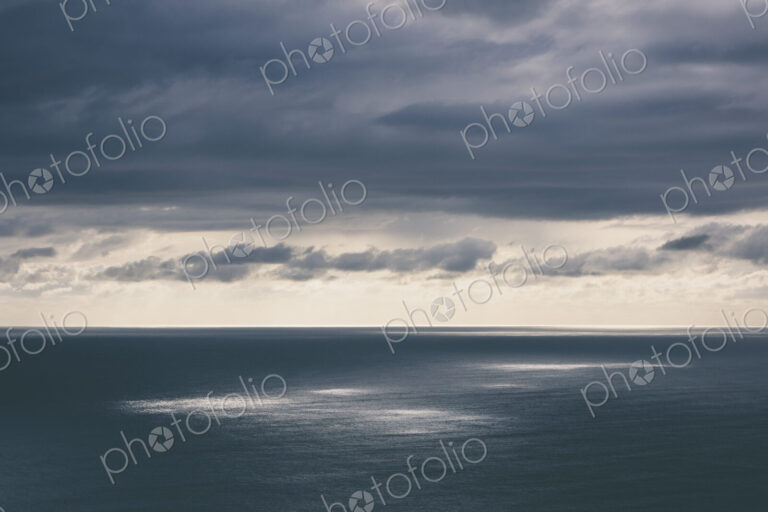 Storm clouds clearing over expansive ocean, dappled sunlight on water, northern Oregon…