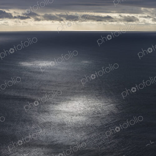 Storm clouds clearing over expansive ocean, dappled sunlight on water, northern Oregon…