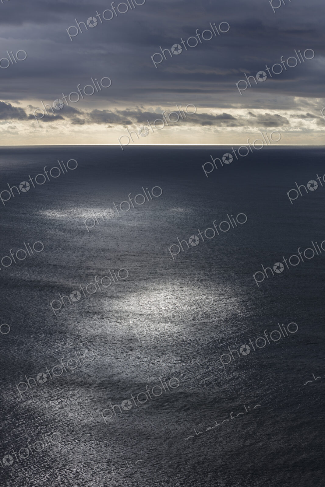 Storm clouds clearing over expansive ocean, dappled sunlight on water, northern Oregon…