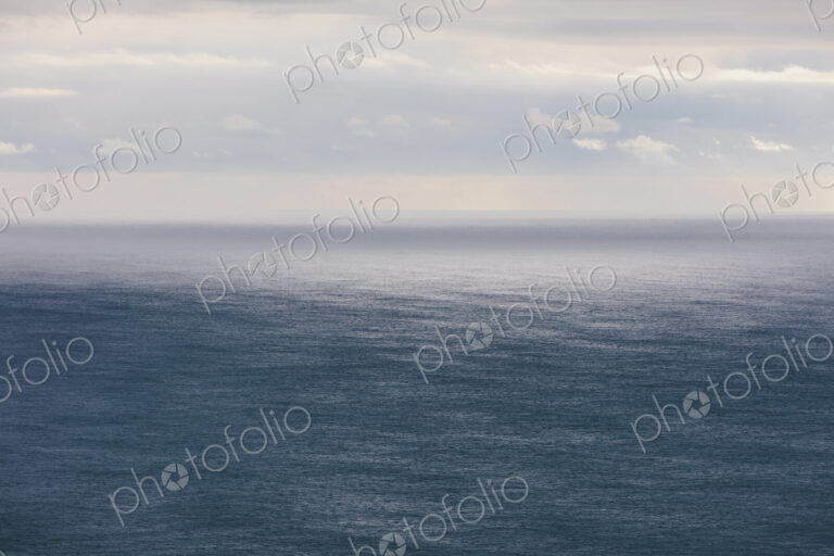 Storm clouds clearing over expansive ocean, dappled sunlight on water, northern Oregon…