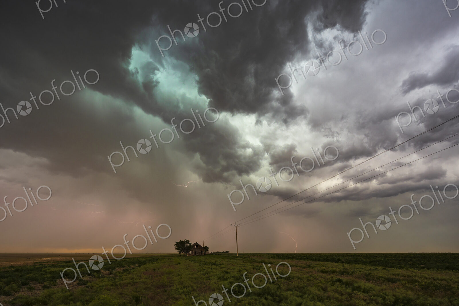 Storm clouds gathering over a small house on the horizon in a flat landscape.