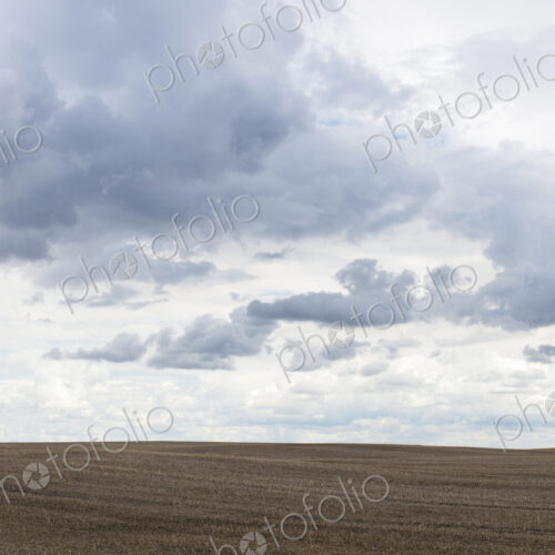Storm clouds over barren farmland, Saskatchewan, Canada.