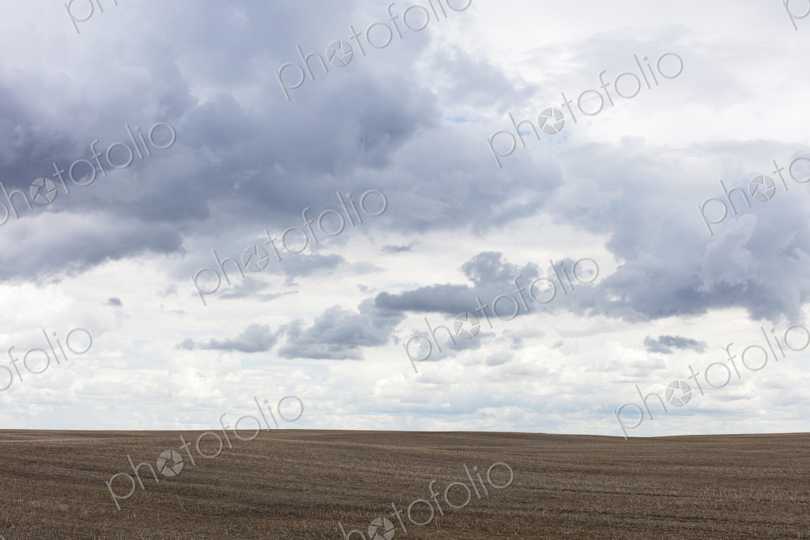 Storm clouds over barren farmland, Saskatchewan, Canada.