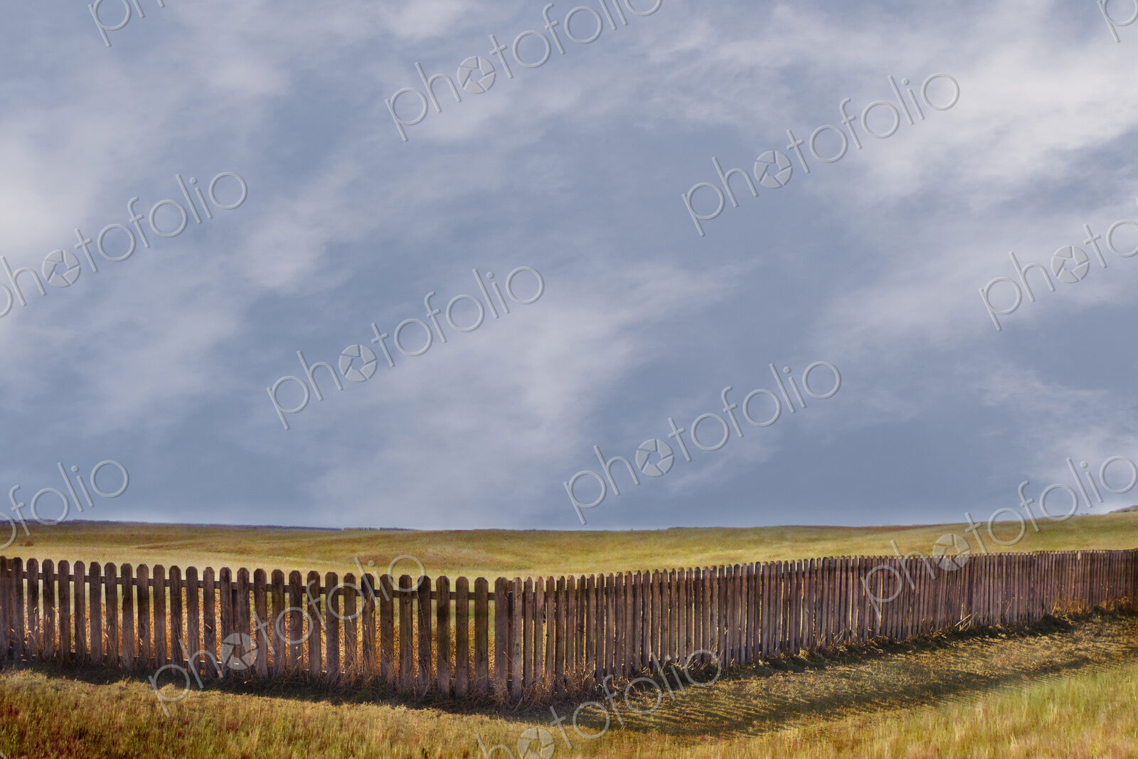 Storm clouds over rural grass fields and fence