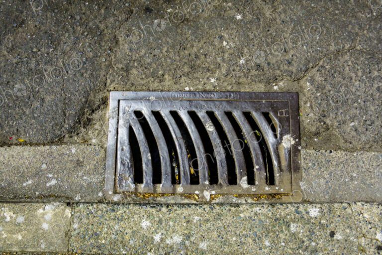 Storm drain on a roadway, a metal grille.