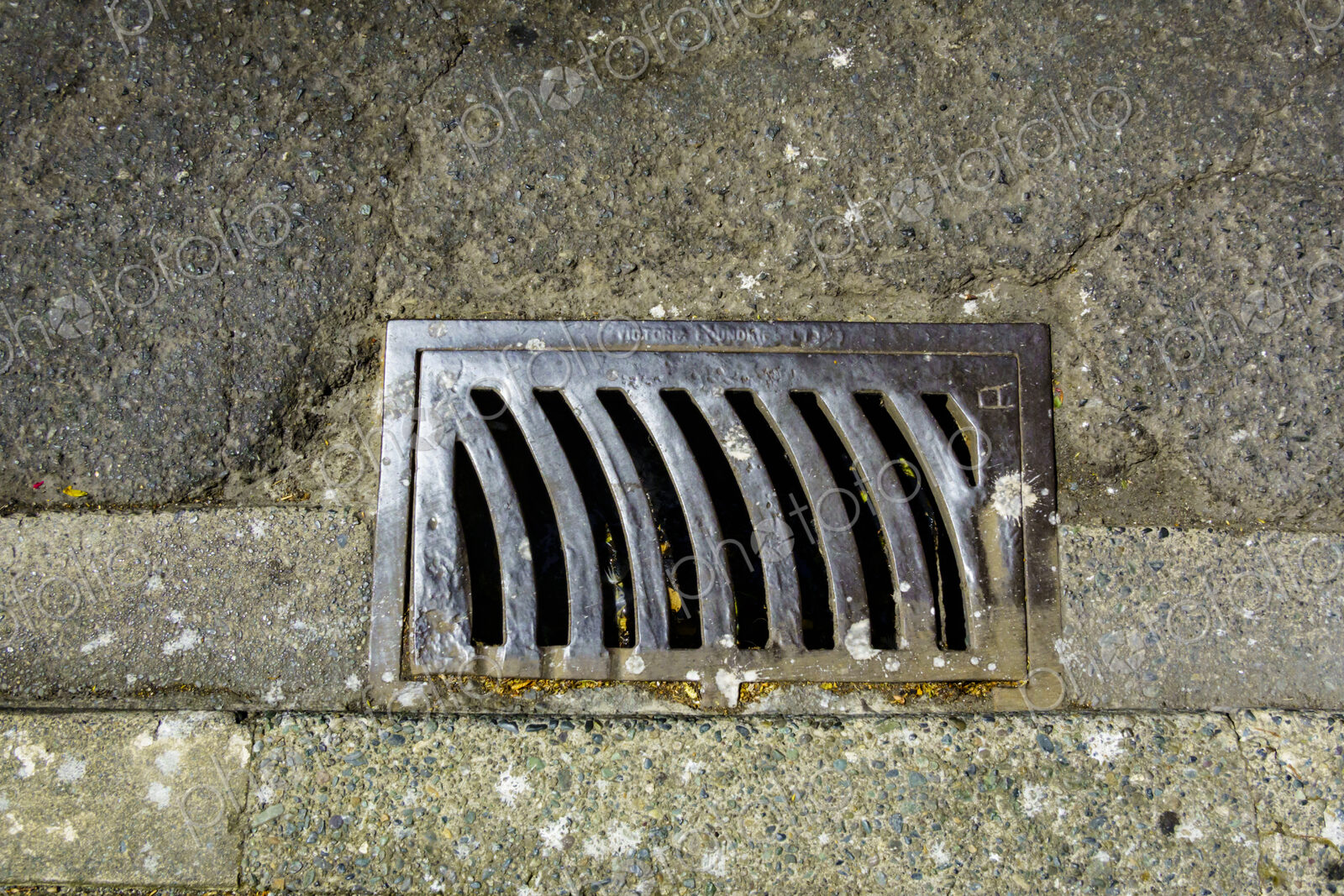 Storm drain on a roadway, a metal grille.
