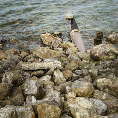 Storm sewer outlet, a pipe hidden under rocks discharging effluents and sewage into… Storm sewer outlet, a pipe hidden under rocks discharging effluents and sewage into…