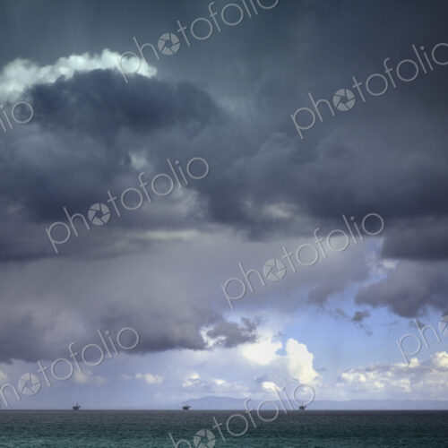 Stormy sky over oil drilling platforms in ocean Stormy sky over oil drilling platforms in ocean