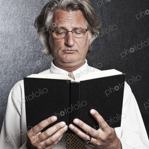 Studio portrait of caucasian man actor holding and reading from a book. Studio portrait of caucasian man actor holding and reading from a book.