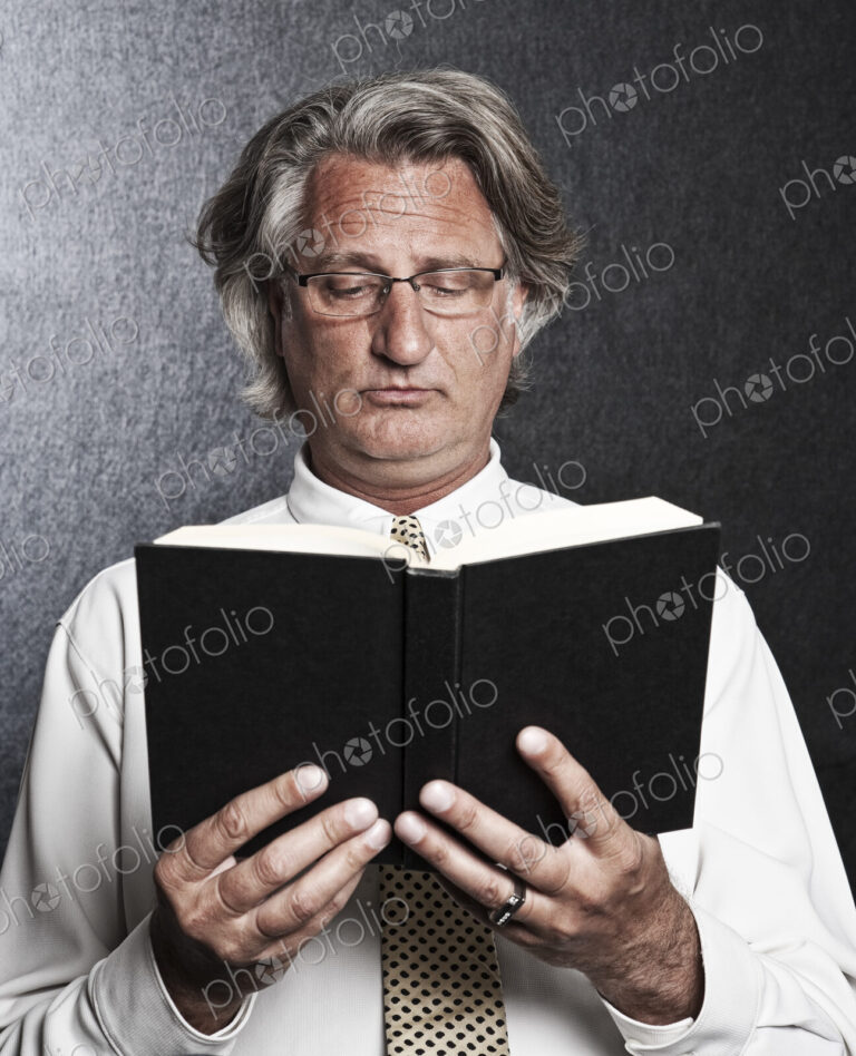 Studio portrait of caucasian man actor holding and reading from a book.