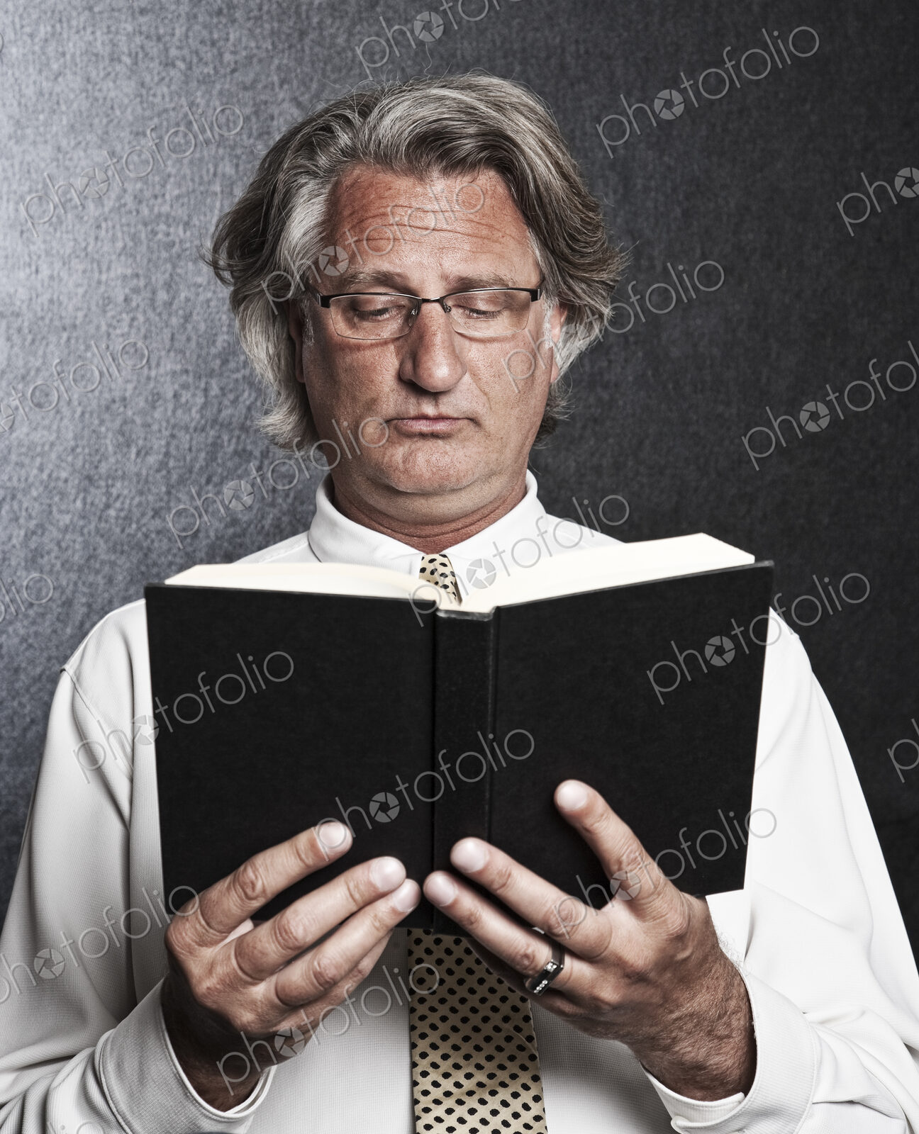 Studio portrait of caucasian man actor holding and reading from a book.