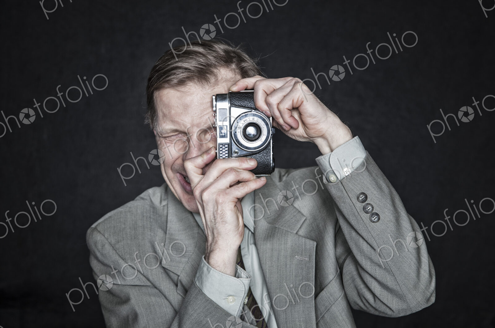 Studio portrait of caucasian man actor using a camera, squinting and focussing.
