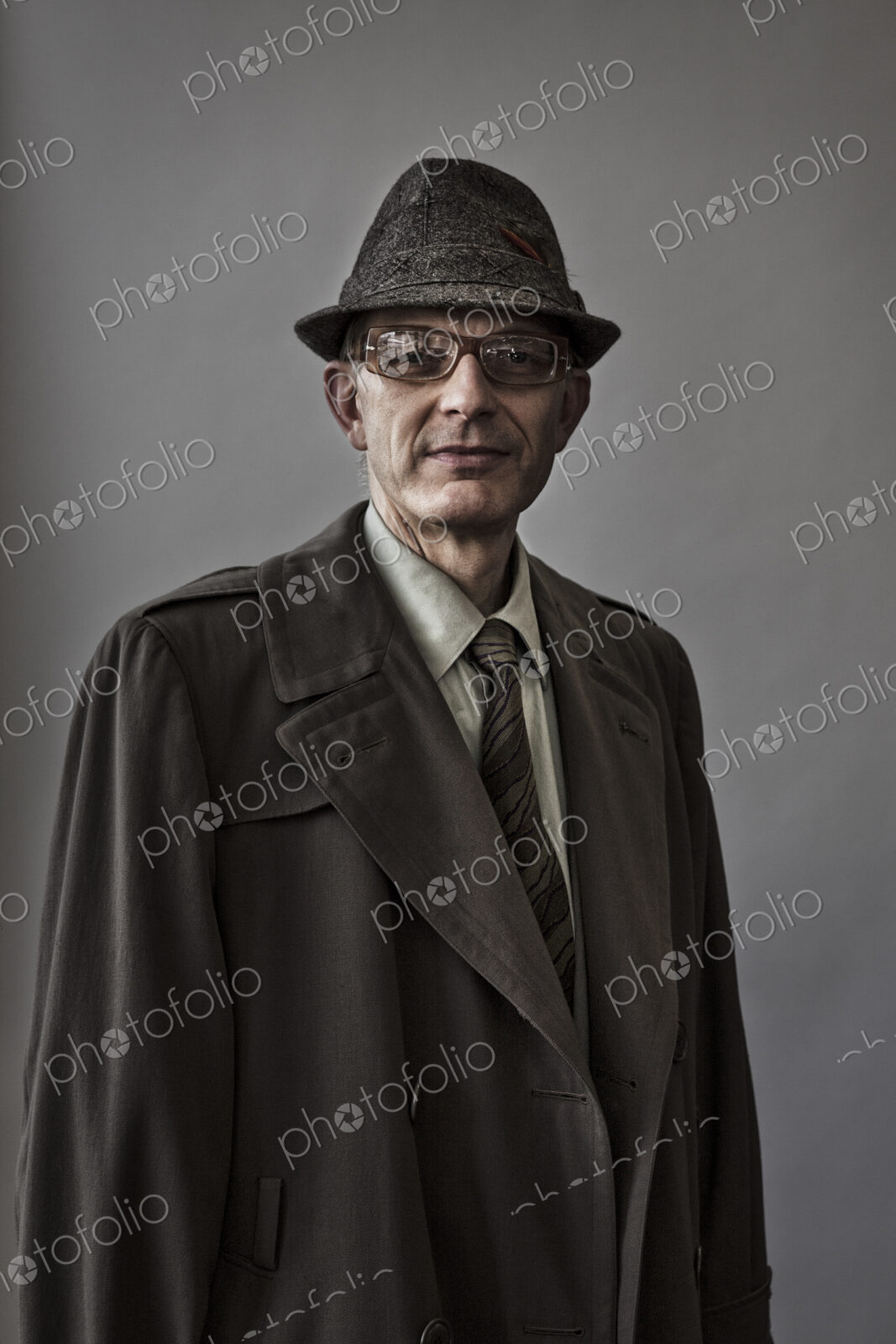 Studio portrait of caucasian man actor with a hat and overcoat on.