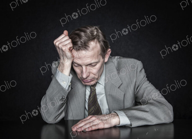 Studio portrait of caucasian man actor with his hand on his head looking down.
