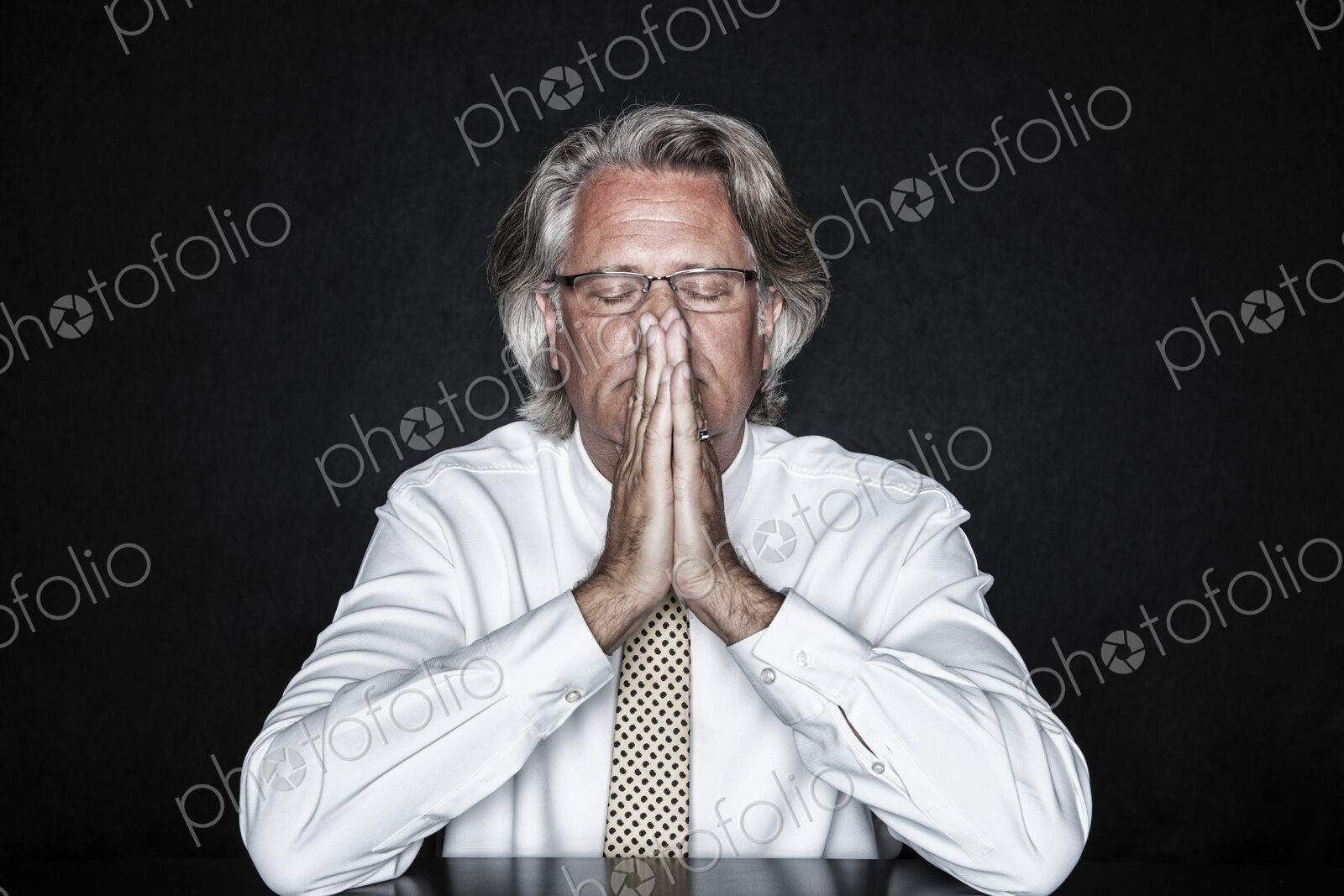 Studio portrait of caucasian man actor with his hands steepled, palms pressed together…