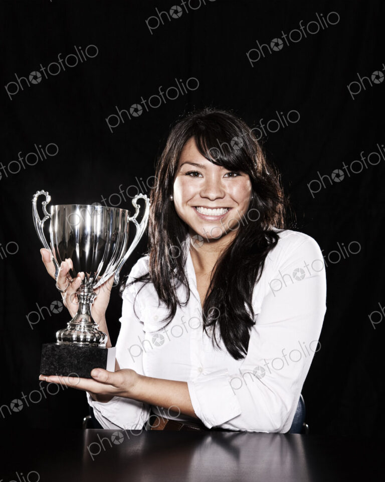 Studio portraits of an Asian woman holding a trophy.