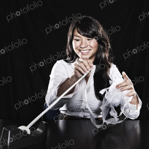 Studio portraits of an Asian woman with sticky tape tangled in her fingers.