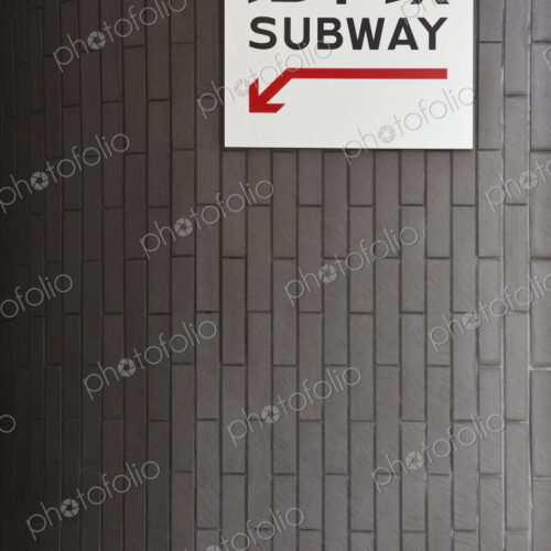Subway entrance sign and red arrow in Western script and Japanese characters.
