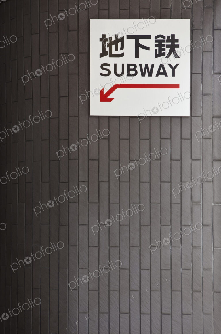 Subway entrance sign and red arrow in Western script and Japanese characters.