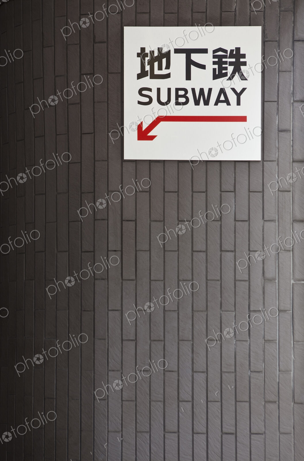 Subway entrance sign and red arrow in Western script and Japanese characters.