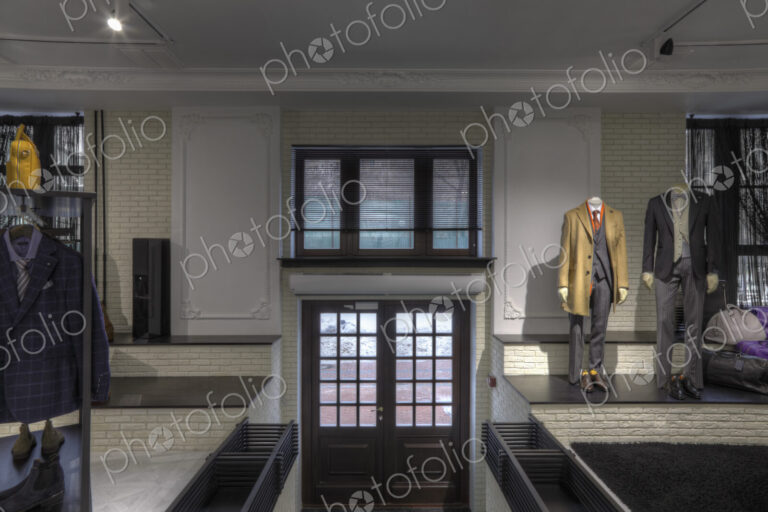 Suits on mannequins near doorway of clothing store for men
