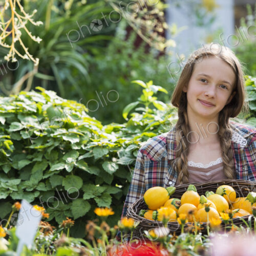 Summer on an organic farm. A girl holding a basket of fresh squash vegetables.