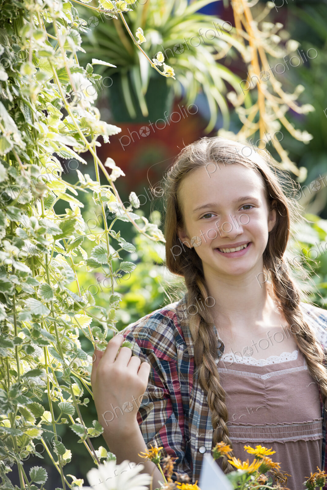 Summer on an organic farm. A young girl in a plant nursery full of flowers.