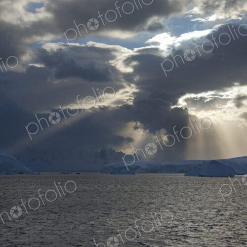 Sun breaking through the storm clouds hitting the icebergs along the west coast of the… Sun breaking through the storm clouds hitting the icebergs along the west coast of the…