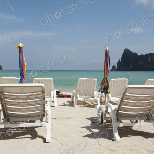 Sun loungers and umbrellas on a beach in the Andaman islands off the coast of Thailand.