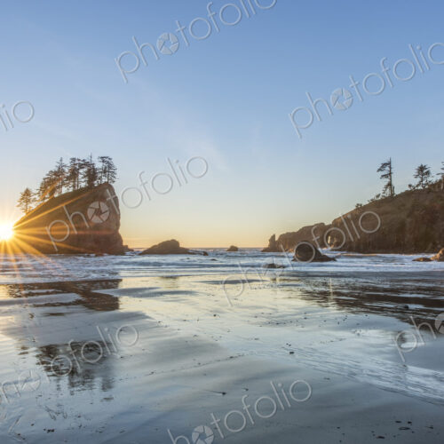 Sun rising over rock formations on beach