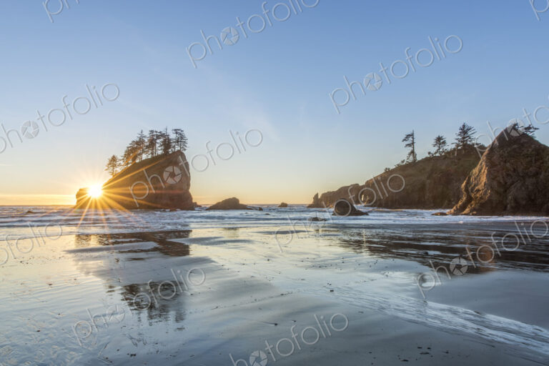 Sun rising over rock formations on beach